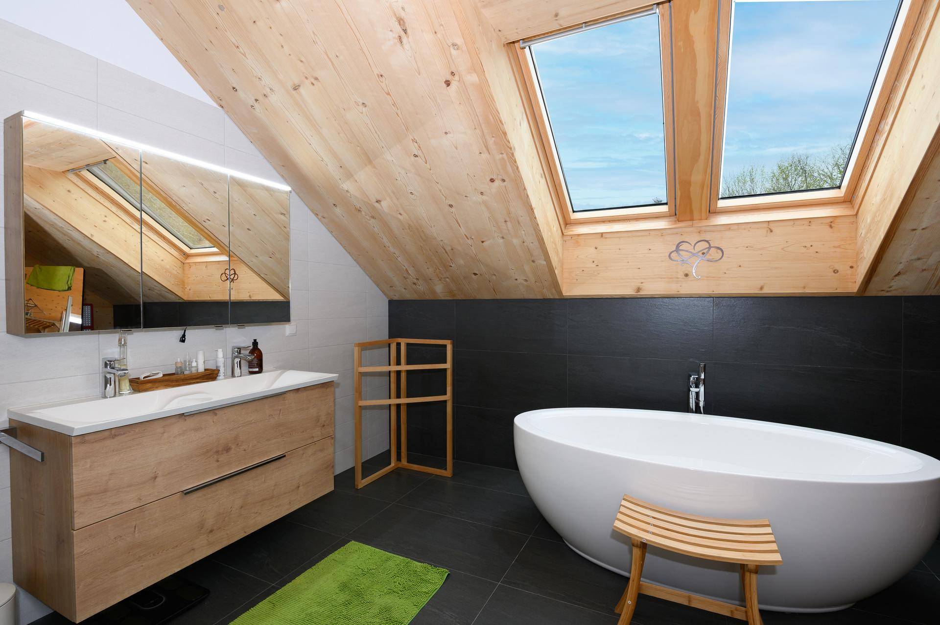 Modernes Badezimmer im Dachgeschoss mit freistehender Badewanne und Dachfenstern.