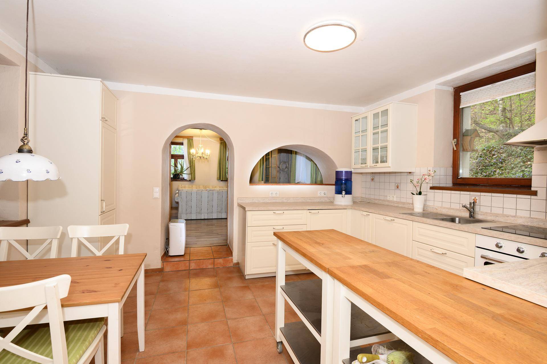 Helle Landhausküche mit Terracotta-Fliesen, Holzarbeitsplatte und Essbereich.