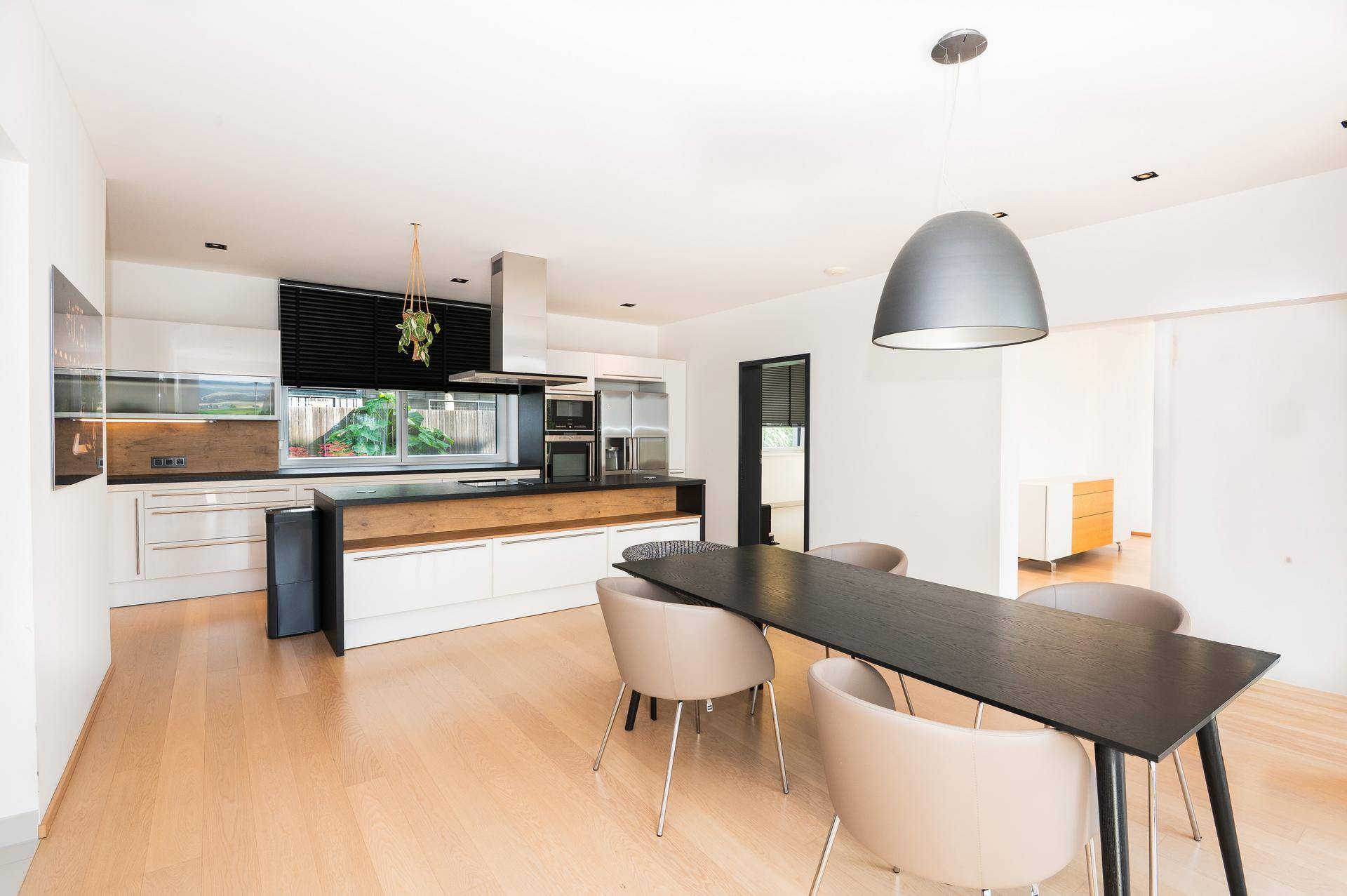 Stilvolle offene Küche mit Essbereich, Kochinsel und Holzboden in modernem Design.