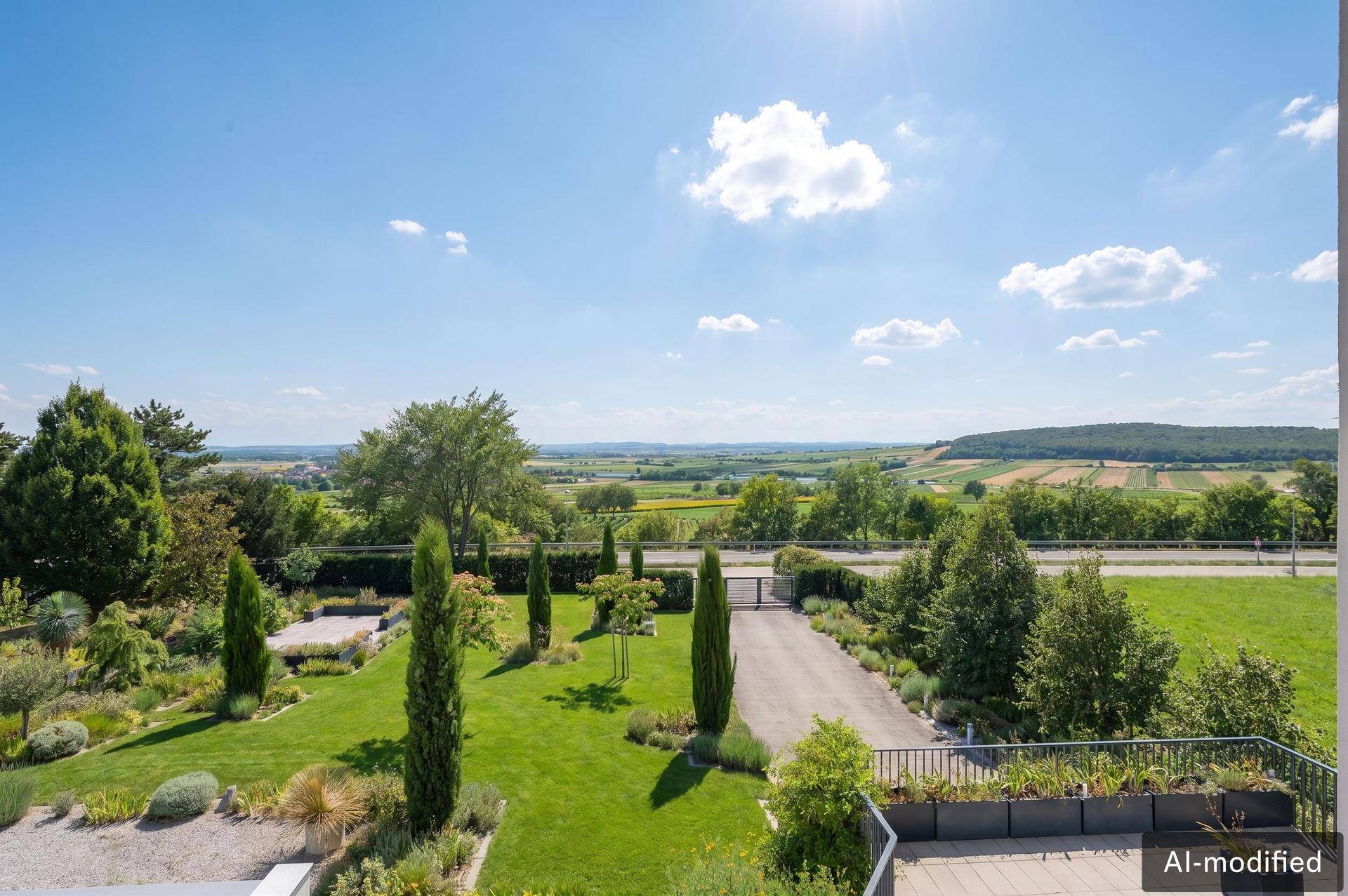 Weitläufiger Garten mit Zufahrt und Panoramablick über die umliegende grüne Landschaft.