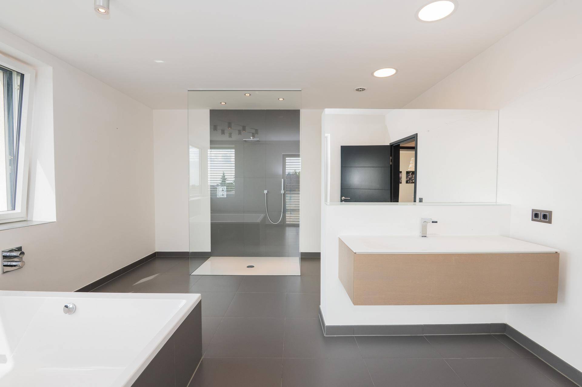 Modernes Badezimmer mit begehbarer Dusche, Badewanne, schwebendem Waschtisch und Fliesenboden.