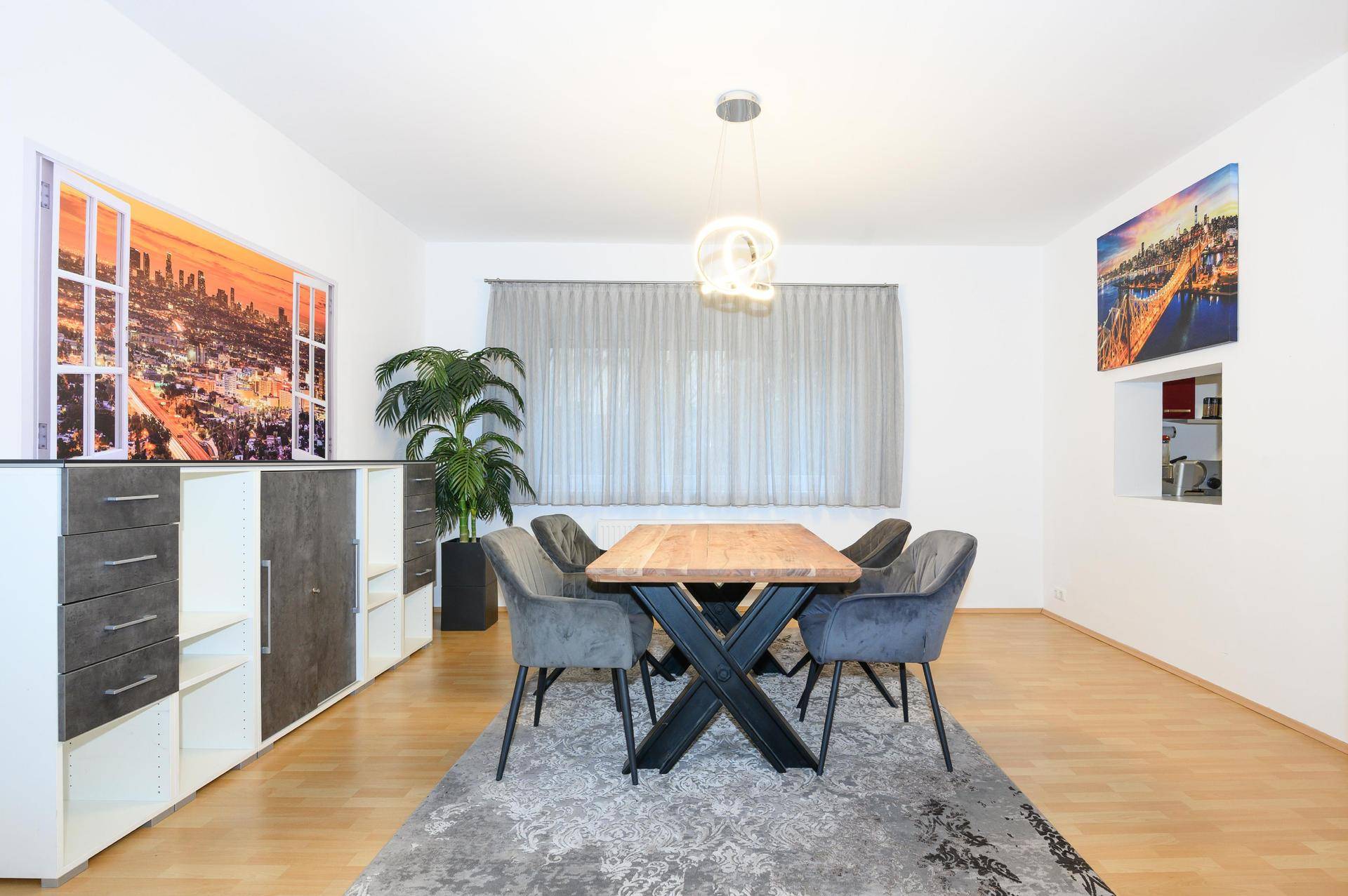 Geräumiger Essbereich mit Holztisch, Teppich und dekorativen Wandbildern.