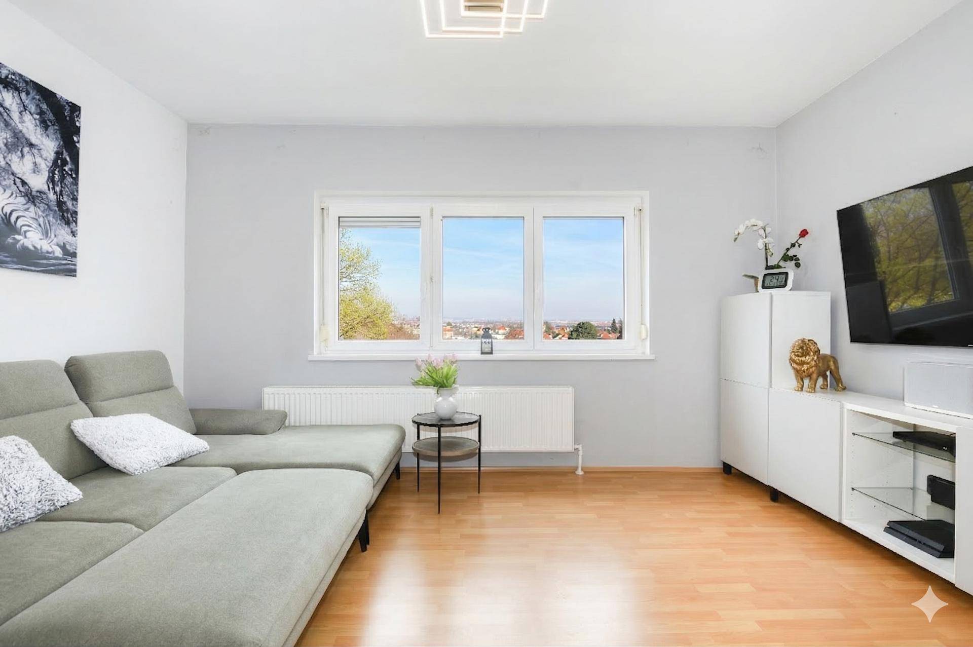 Gemütliches Wohnzimmer mit Ecksofa, Holzboden und weitem Blick über die Landschaft.