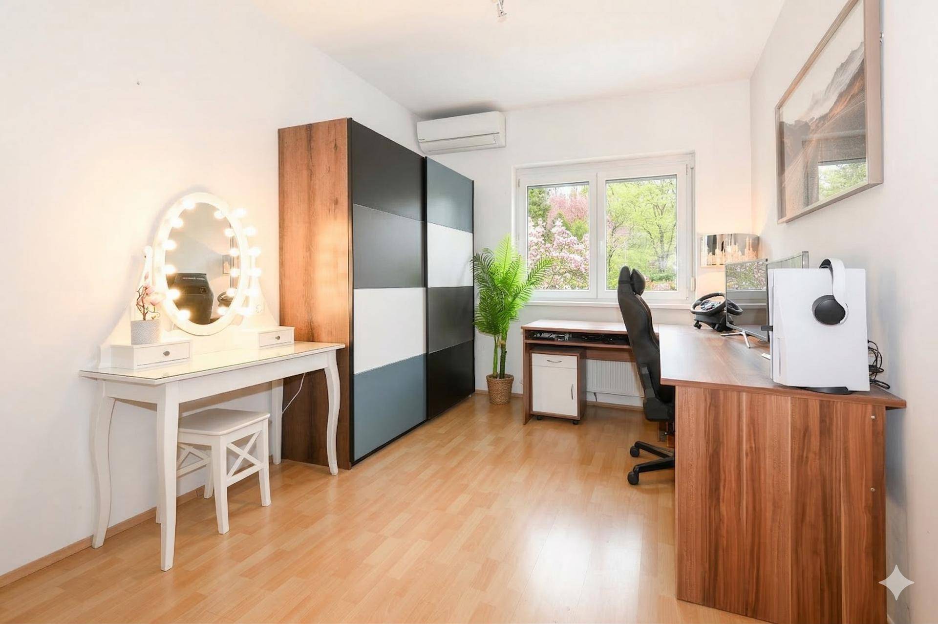 Helles Arbeitszimmer mit Holzboden, Schreibtisch, Schminktisch und Klimaanlage.
