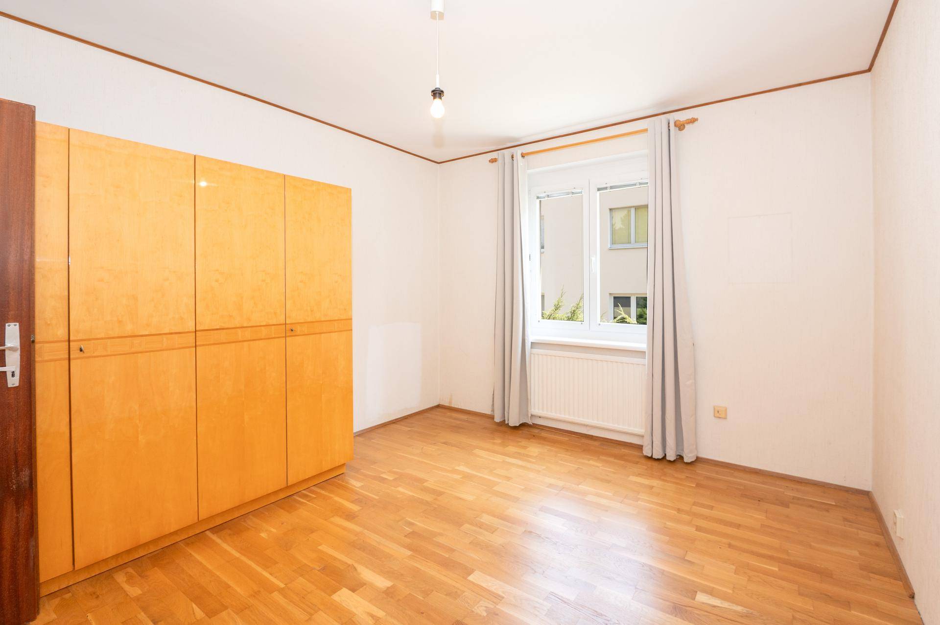 Helles Zimmer mit Parkettboden und großem Holzschrank, ideal als Schlaf- oder Ankleidezimmer.