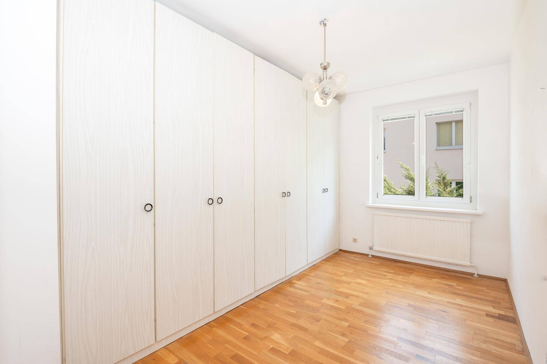 Geräumiges Zimmer mit Parkettboden und weißem Einbauschrank, gut beleuchtet durch das Fenster.