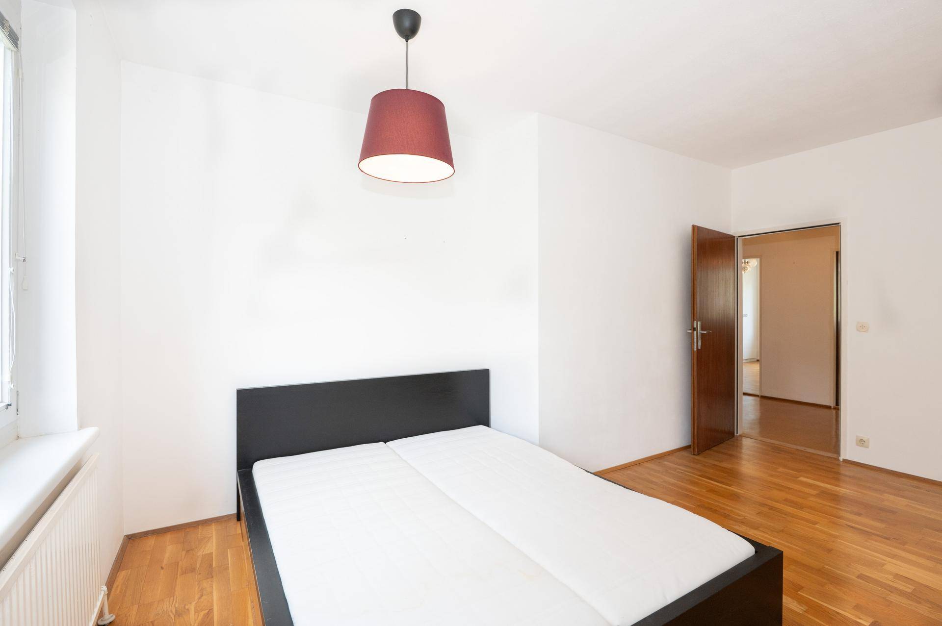 Helles Schlafzimmer mit Parkettboden, einem Doppelbett und Zugang zu einem weiteren Raum.