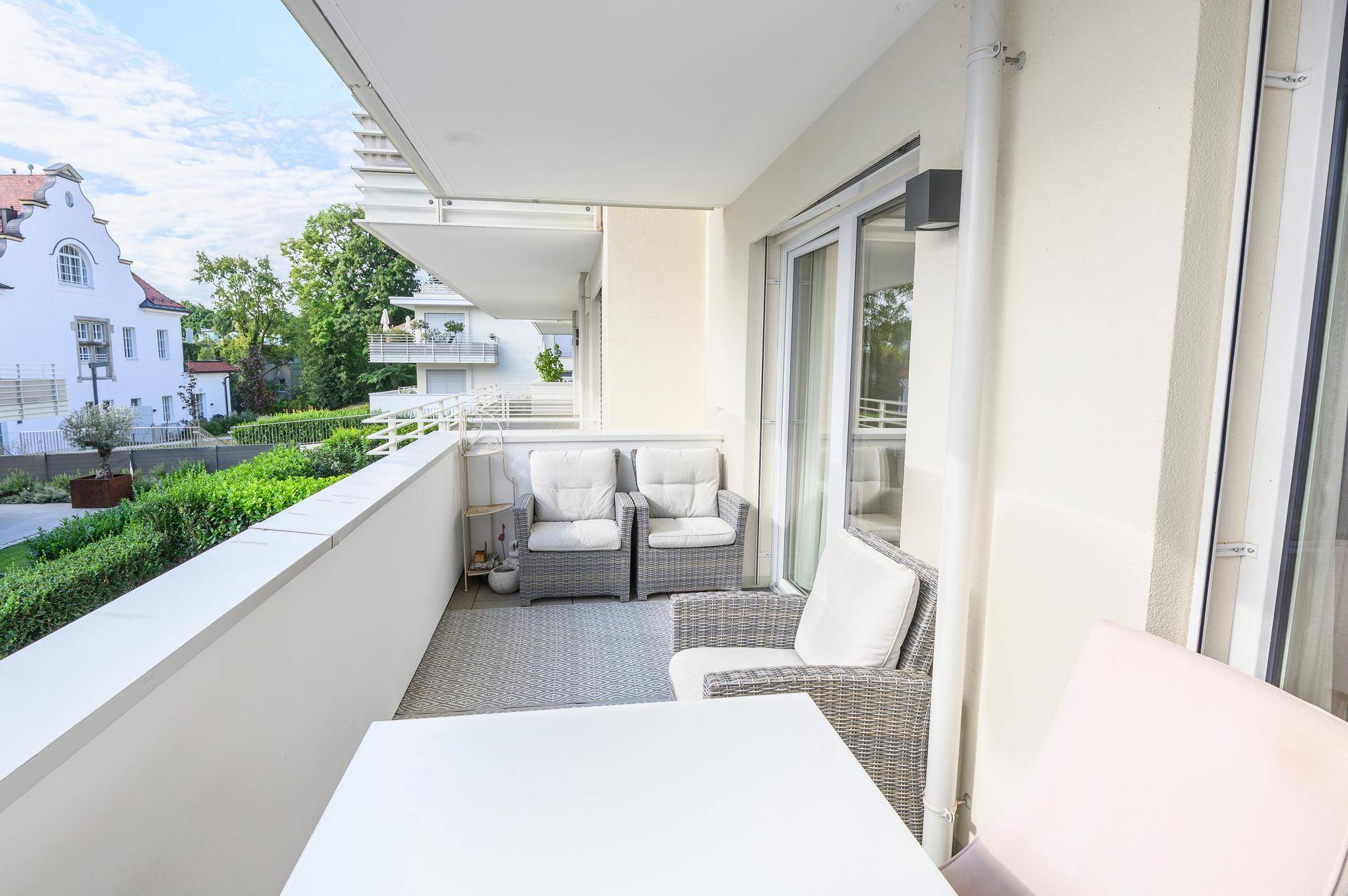 Geräumiger Balkon mit bequemen Korbsesseln und Blick auf die umliegende Bebauung.