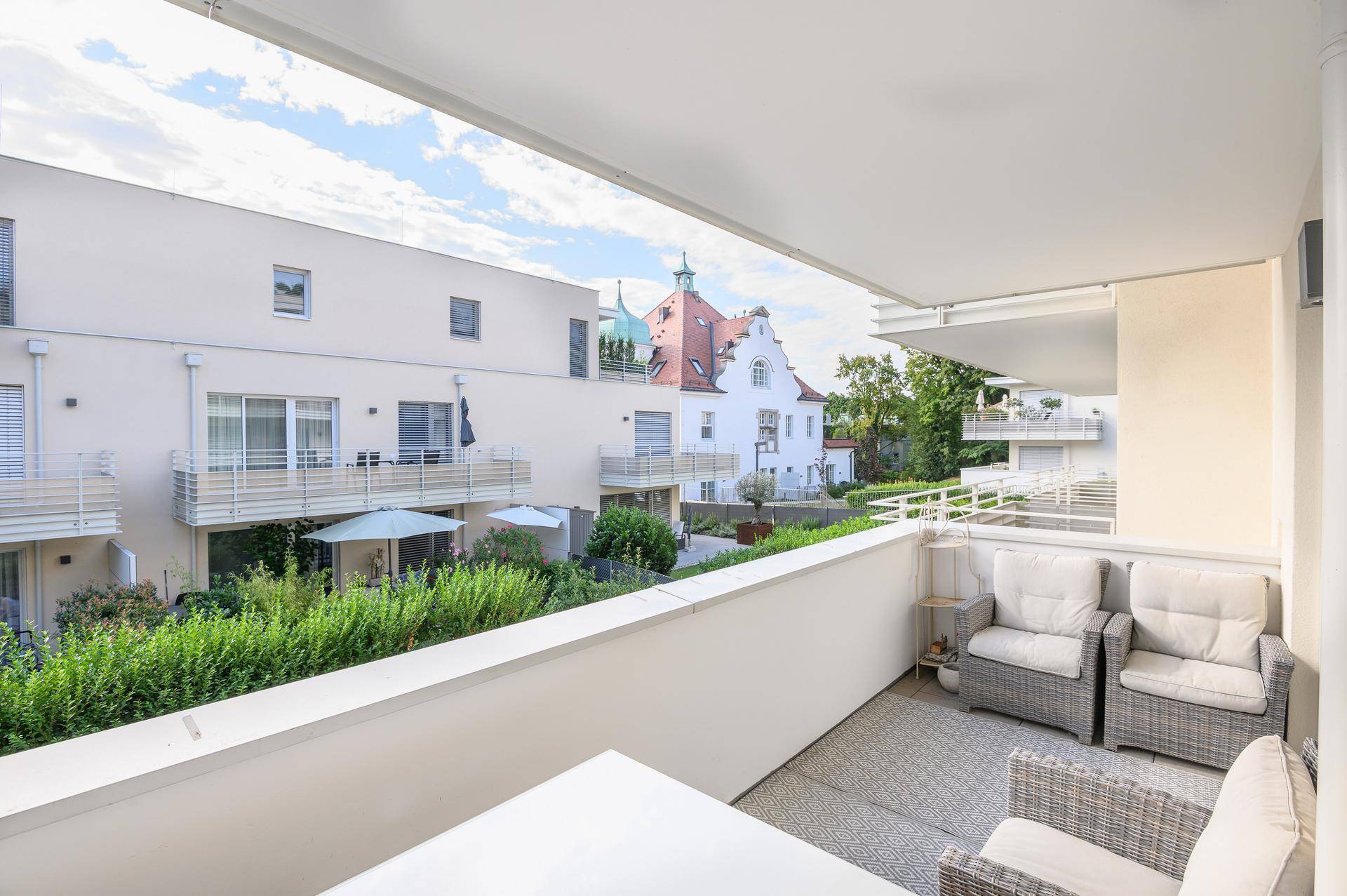 Gemütlicher Balkon mit Sitzgelegenheiten und Blick auf die grüne Wohnanlage.
