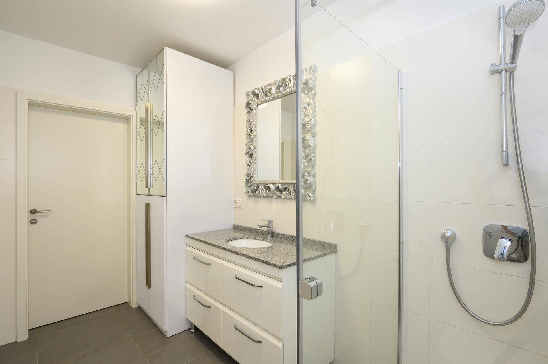 Funktionales Badezimmer mit Duschkabine, Waschtischunterschrank und großem Spiegelschrank.