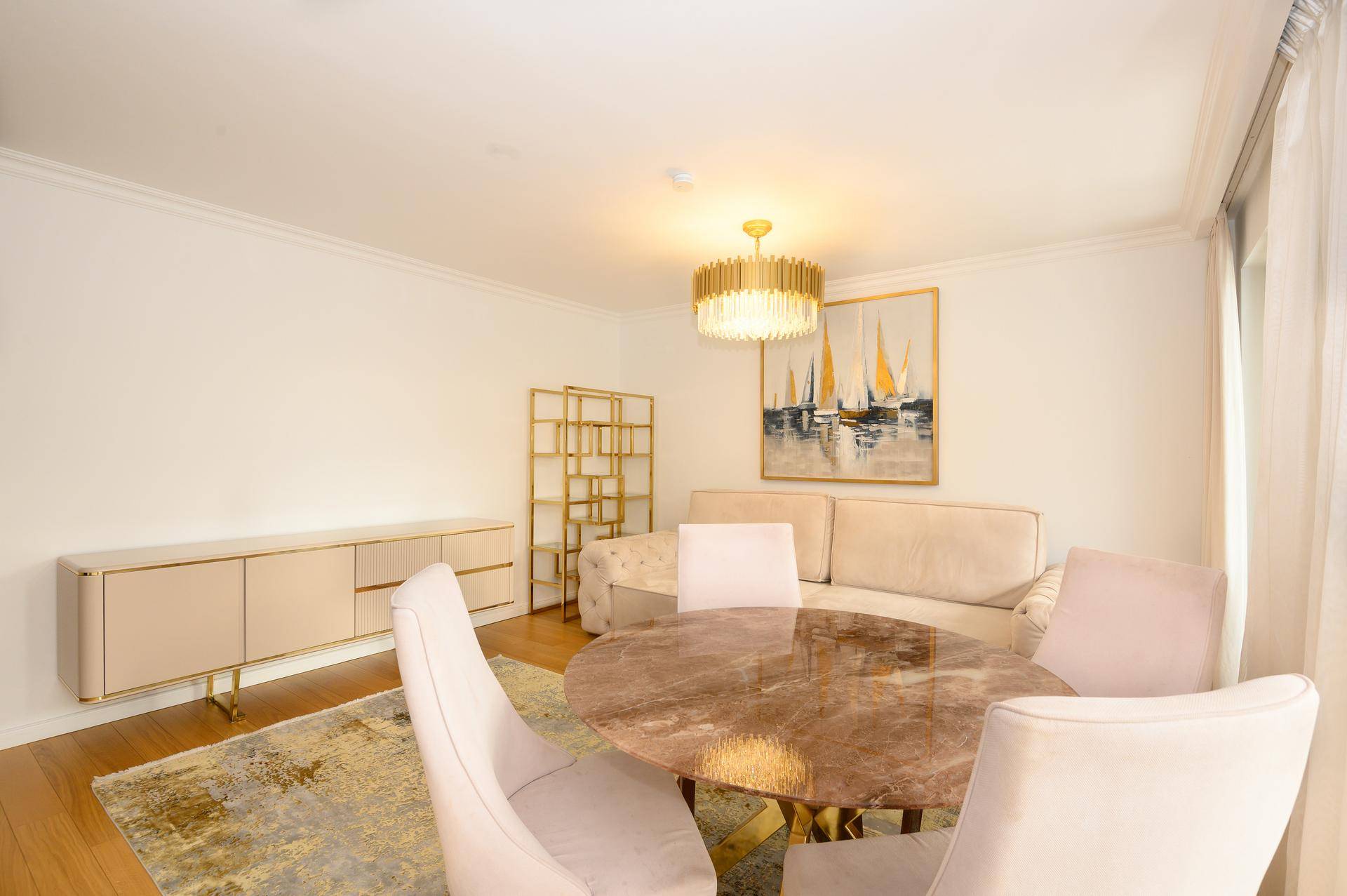 Eleganter Wohn-Essbereich mit beigem Sofa, Marmortisch und goldfarbenen Akzenten.