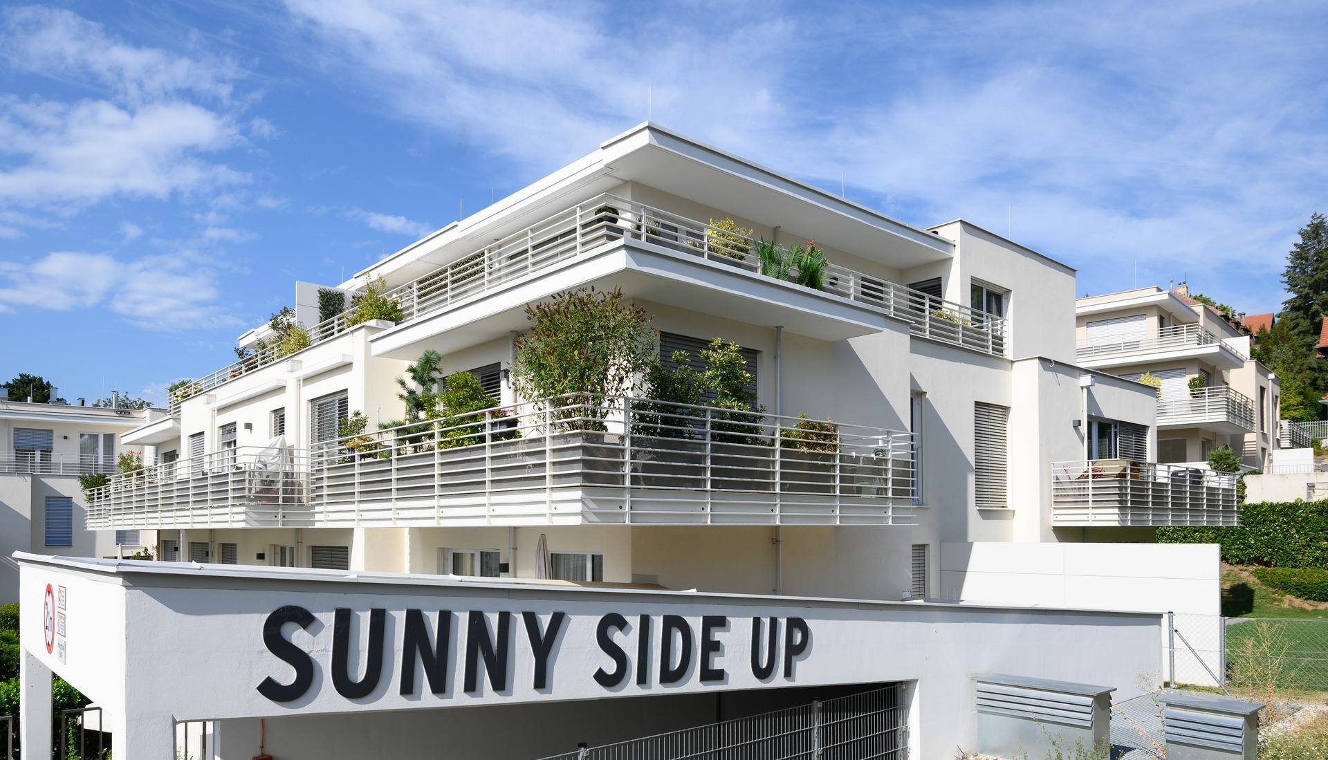 Moderne Wohnanlage mit mehreren Balkonen und der Aufschrift "SUNNY SIDE UP".