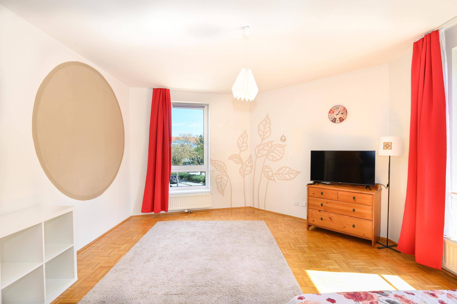 Geräumiges Schlafzimmer mit Holzboden, großen Fenstern und dekorativer Wandgestaltung.