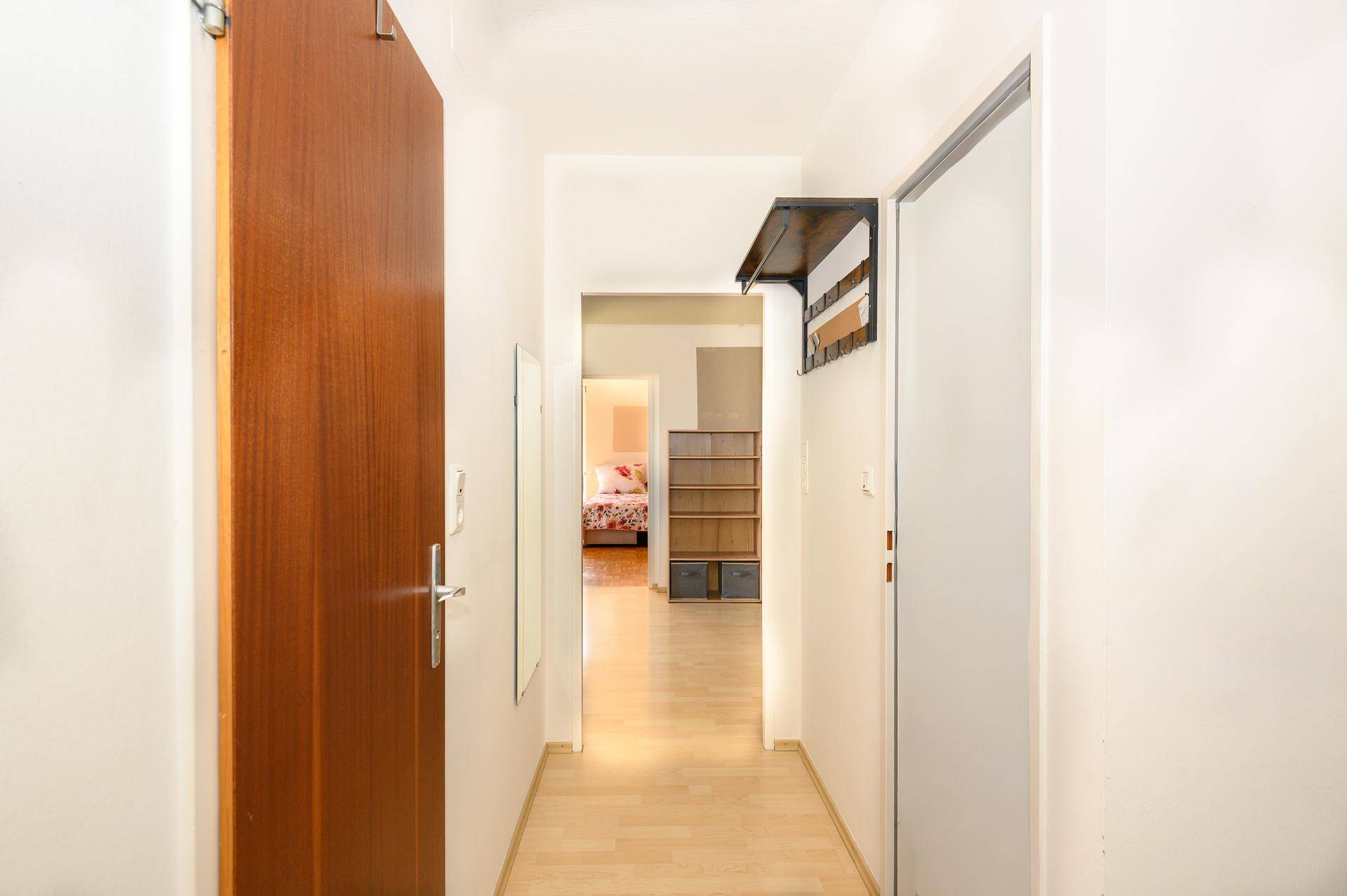 Heller Flur mit Holzboden, Garderobe und Zugang zu weiteren Räumen.