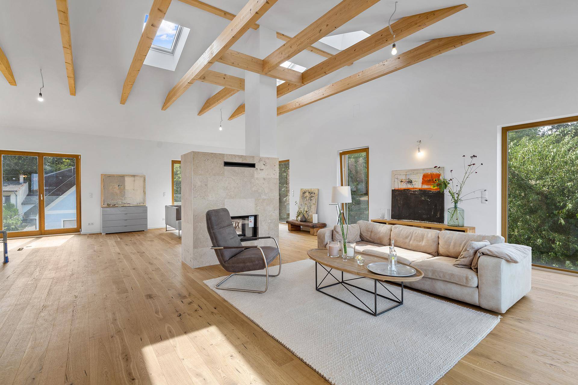 Helles und geräumiges Wohnzimmer mit hohen Decken, Holzbalken und modernem Kamin.