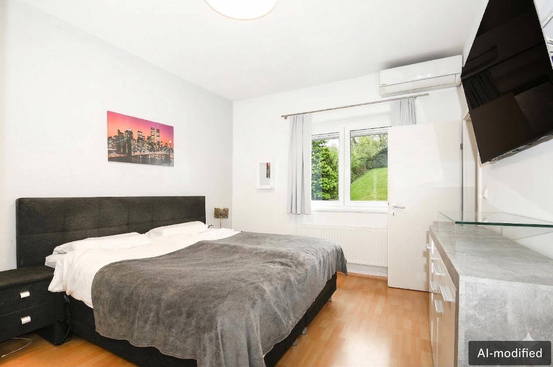 Gemütliches Schlafzimmer mit Doppelbett, Holzboden, Klimaanlage und Blick ins Grüne.
