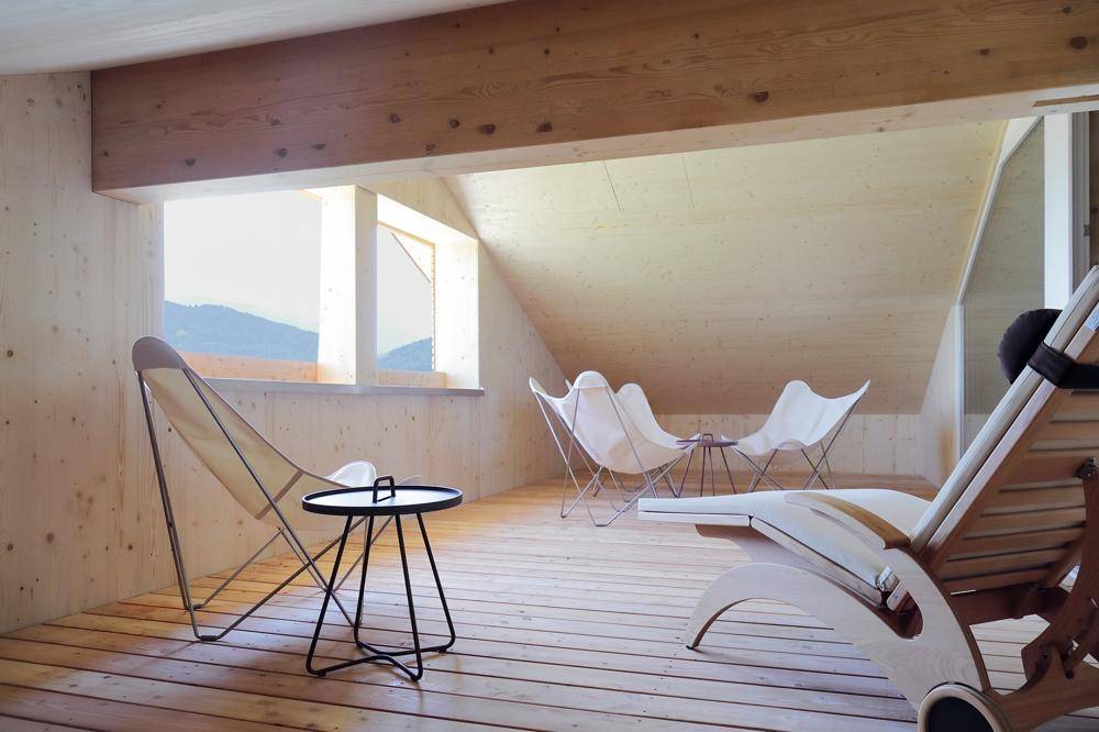 Entspannungsbereich im Dachgeschoss mit Holzverkleidung, bequemen Liegen und weitem Ausblick.