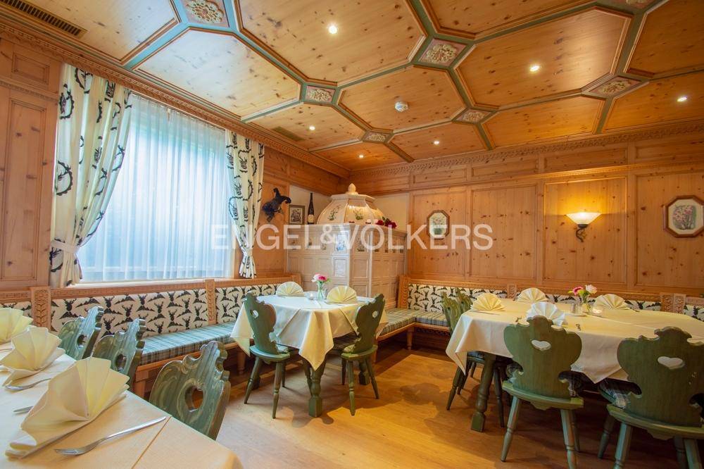 Rustikaler Speisesaal mit Holztäfelung, bemalter Holzdecke und traditionellen Sitzgelegenheiten.