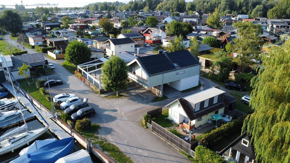 Weitläufige Luftaufnahme des Anwesens mit umliegenden Häusern, einem Yachthafen und viel Grün in der Umgebung.