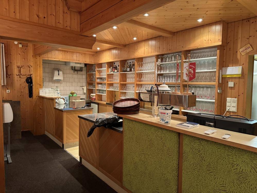 Gemütlicher Barbereich mit viel Holzverkleidung, Regalen voller Gläser und einer Theke.