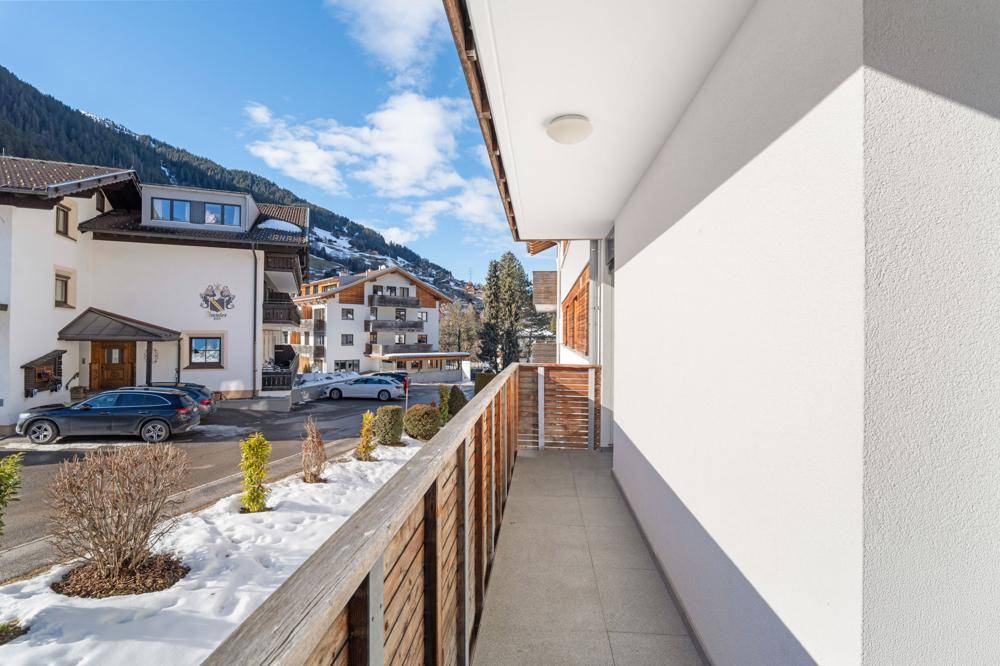 Langer Balkon mit Holzzaun und Blick auf die verschneite Berglandschaft.