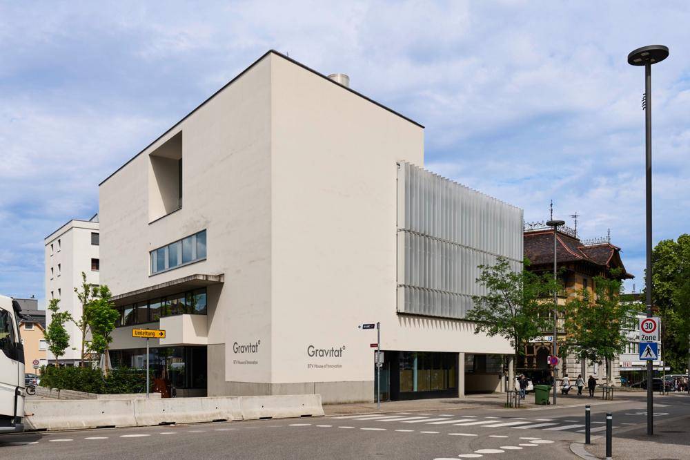 Modernes Gebäude mit "Gravitat" Beschriftung an einer Straßenecke, zeigt zeitgenössische Architektur und städtisches Umfeld.
