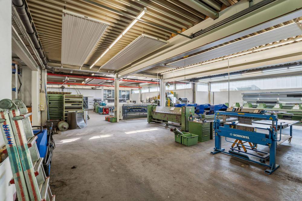 Große Werkshalle mit Maschinen, Metallbearbeitungsgeräten und Betonboden.