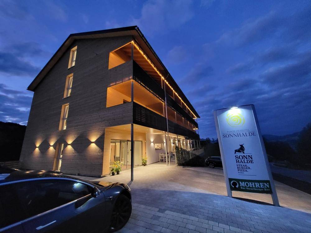 Hotelgebäude bei Nacht mit beleuchteten Balkonen und Eingangsbereich, umgeben von dunkler Landschaft.