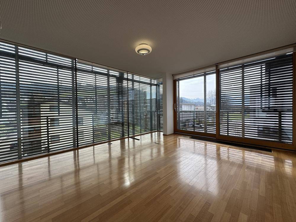 Großer Raum mit Holzboden und einer umlaufenden Fensterfront, die einen weiten Blick ermöglicht.