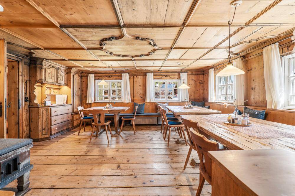 Traditioneller Essbereich mit Holztischen, Holzbänken und Holzvertäfelungen an Wänden und Decke.