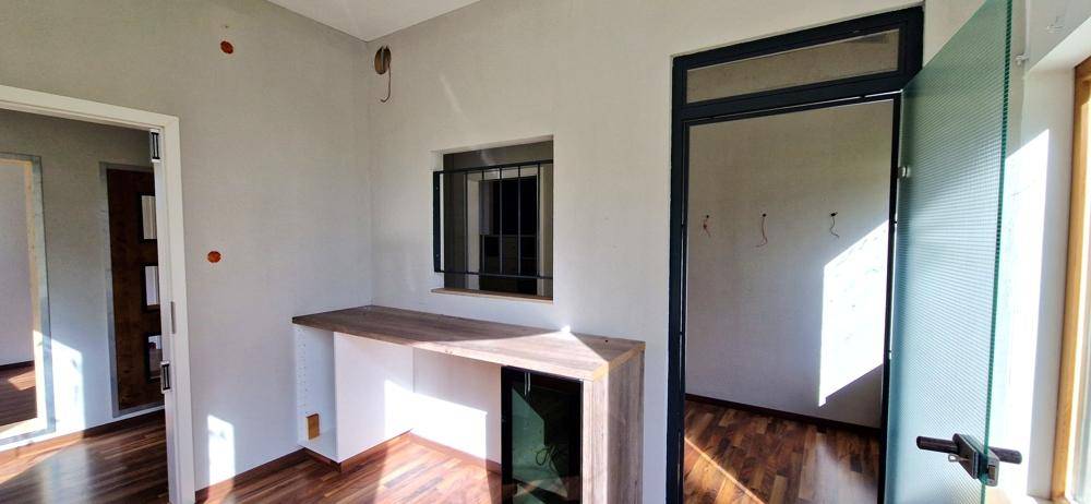 Kleiner Raum mit Holzarbeitsplatte, Fenster und Zugang zu einem weiteren Bereich, hell und funktional.