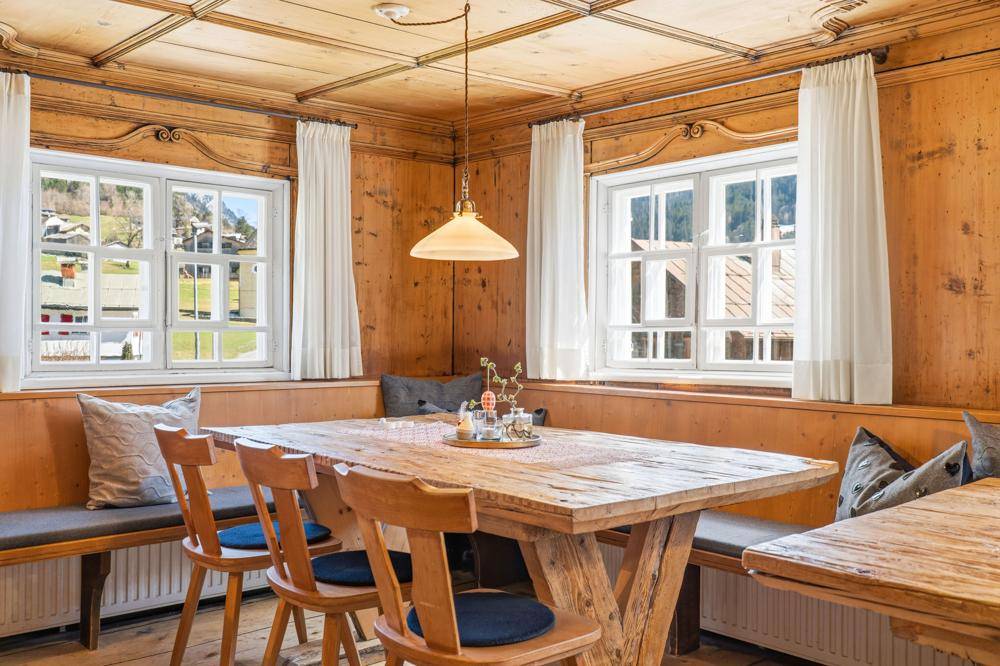 Gemütlicher Essbereich mit Holztisch, Eckbank und Fenstern mit Blick auf die umliegende Landschaft.