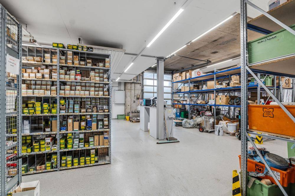 Lagerraum mit hohen Regalen voller Kartons und Produkten, sowie Betonboden.