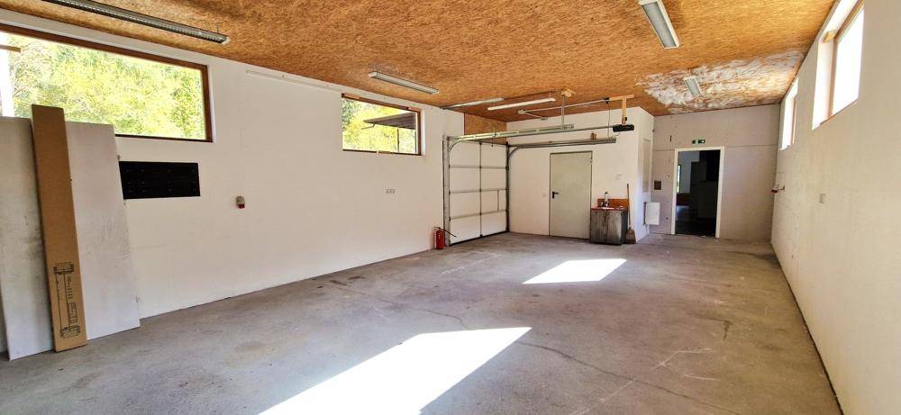 Große Garage mit Rolltor, Betonboden und Fenstern, bietet viel Platz und Tageslicht.