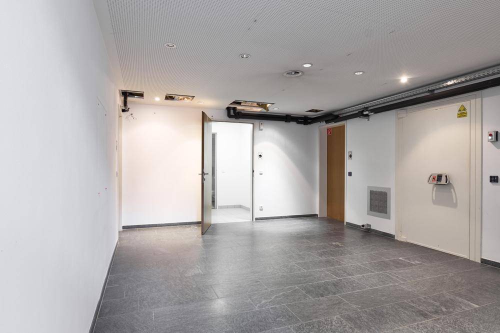 Großer Lagerraum im Untergeschoss mit dunklem Fliesenboden und sichtbaren Installationen an der Decke.