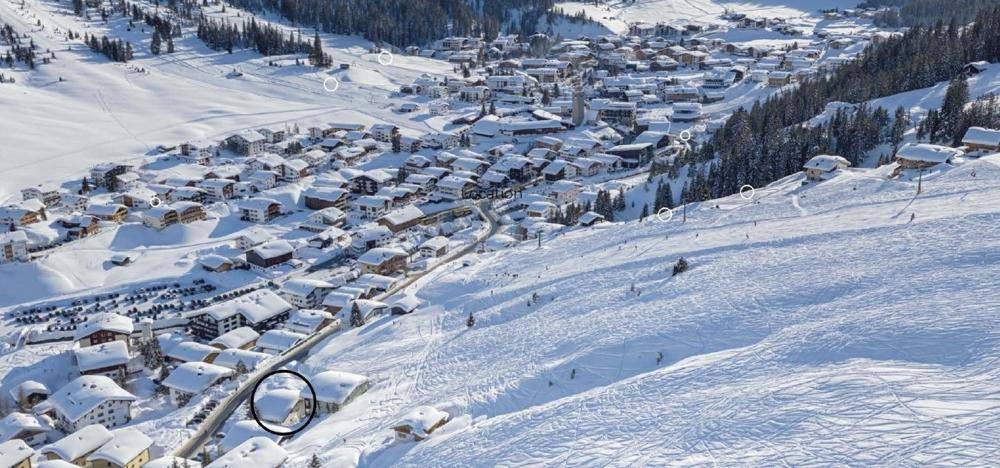 Luftaufnahme eines verschneiten Bergdorfes mit Skipisten und umliegender Natur, bietet eine atemberaubende Aussicht.