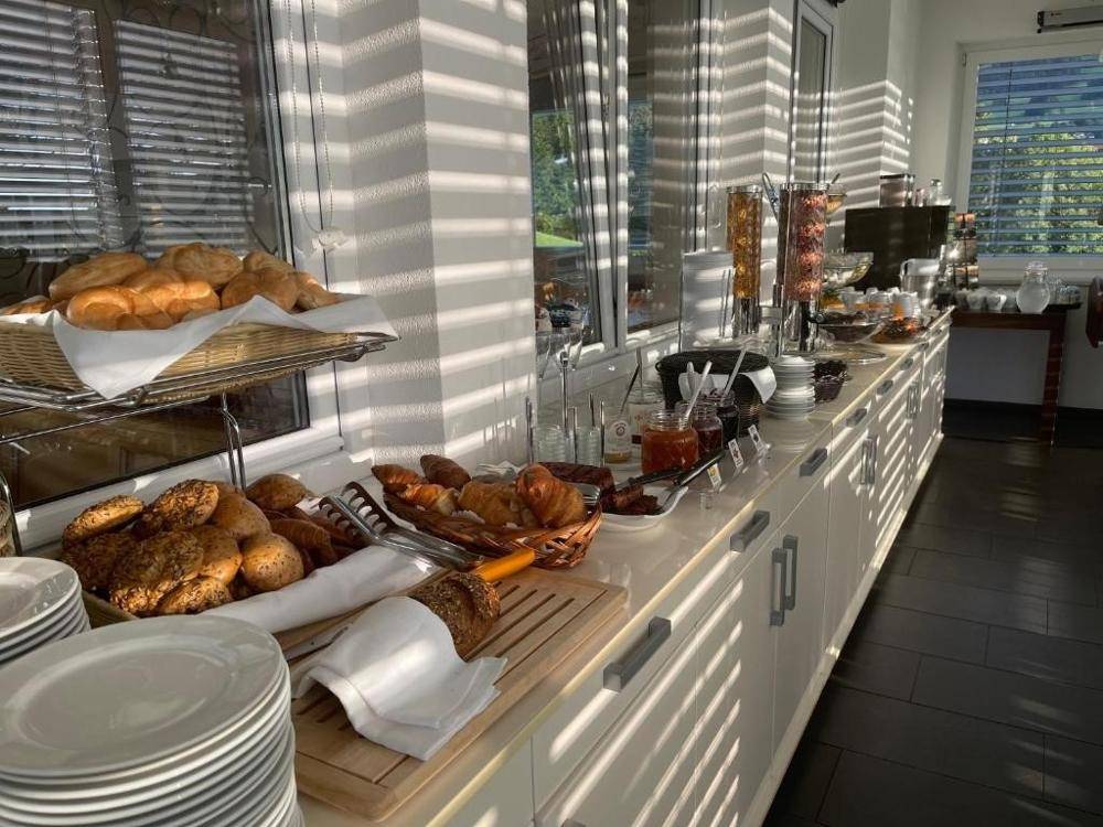 Reichhaltiges Frühstücksbuffet in einem hellen Raum mit großen Fenstern und Jalousien.