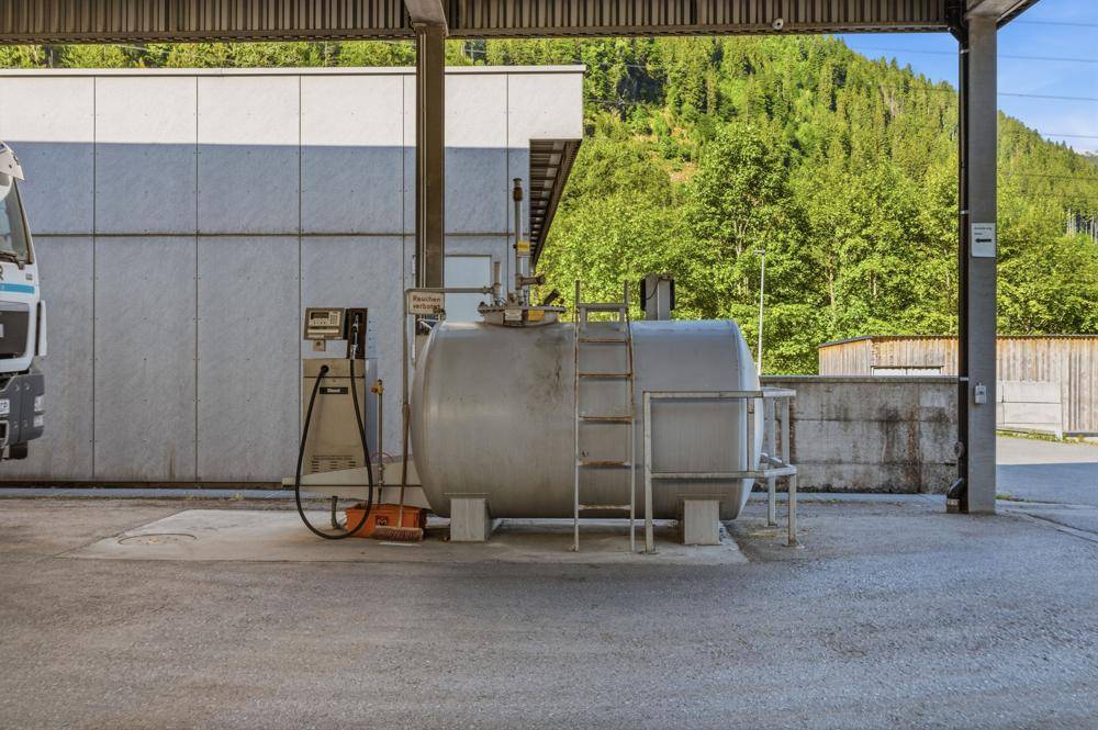 Tankstelle mit großem Kraftstofftank und Zapfsäule im Außenbereich.