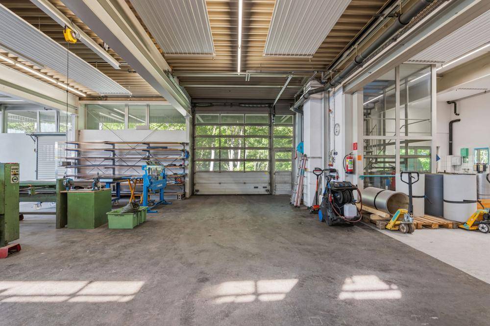 Große Lagerhalle mit Rolltor, Betonboden und viel Tageslicht.