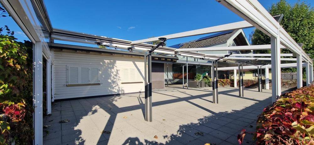 Überdachte Terrasse mit Fliesenboden und Blick auf die umliegende Vegetation, ideal für Entspannung im Freien.