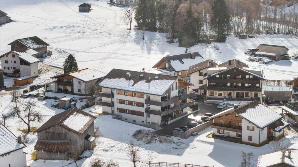 Nahaufnahme eines Wohngebäudes in einer verschneiten Berglandschaft mit traditionellen Häusern.