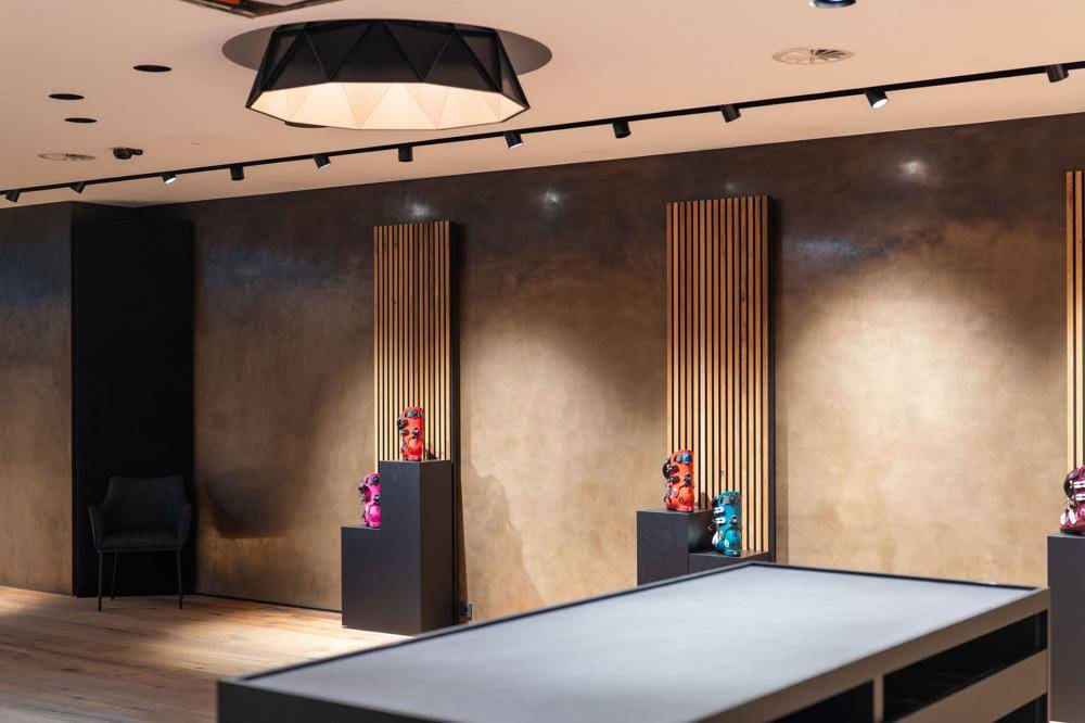 Detailansicht einer modernen Wandgestaltung mit Holzlamellen, indirekter Beleuchtung und Ausstellungsstücken.