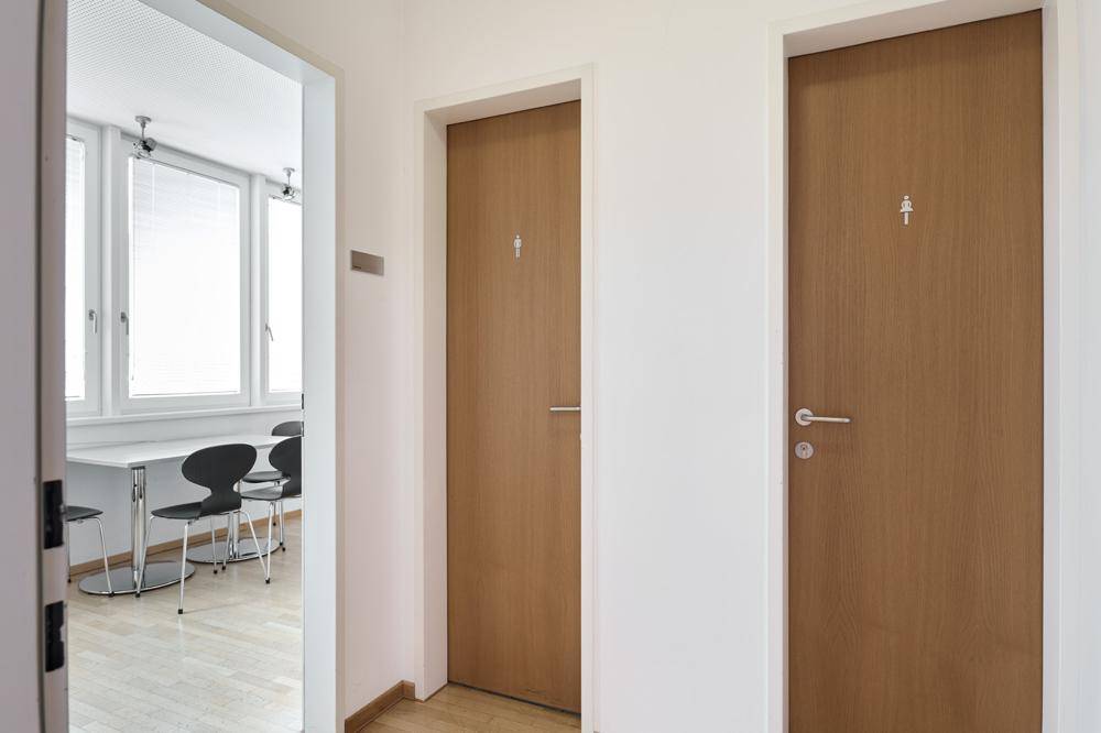 Flur mit Holztüren, die zu verschiedenen Räumen führen, darunter ein Büro und Toiletten.