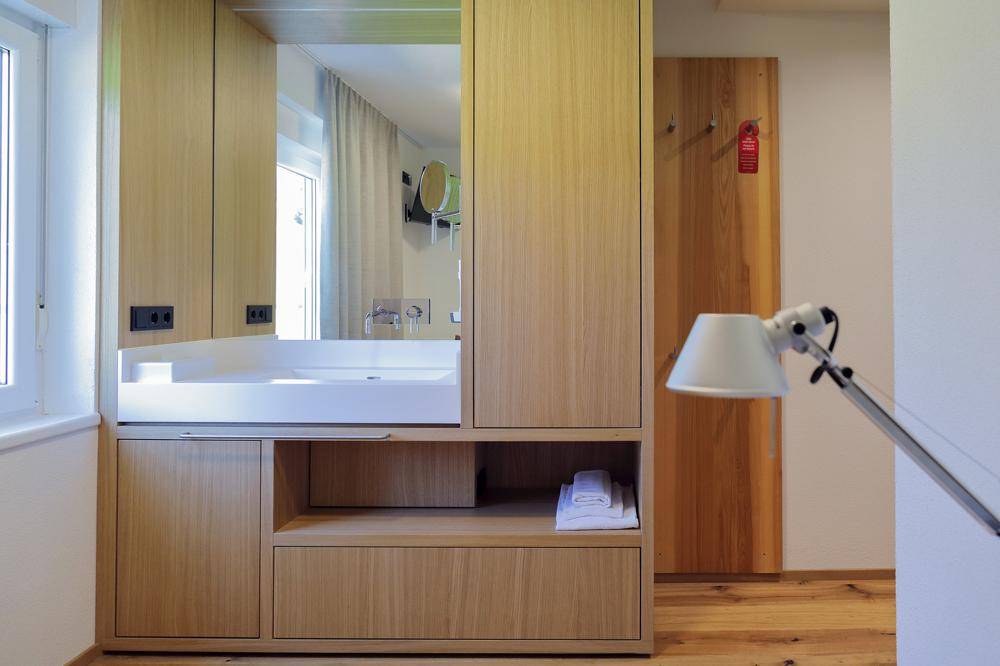 Modernes Badezimmer mit Holzwaschtisch, integriertem Spiegel und Holzboden im angrenzenden Bereich.