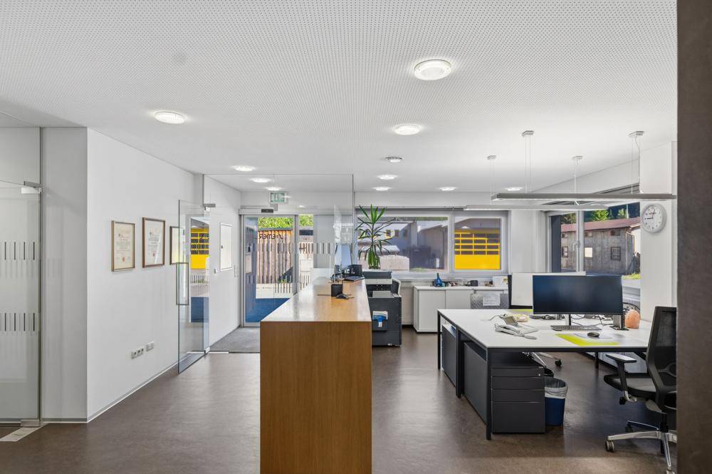 Helles Großraumbüro mit modernen Arbeitsplätzen, Holzelementen und viel Tageslicht.