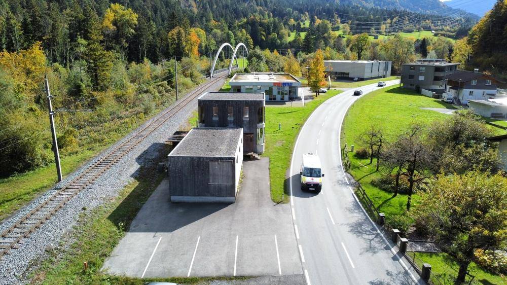 Luftaufnahme des Gebäudes mit Parkplätzen und der umliegenden Landschaft, nahe einer Straße.