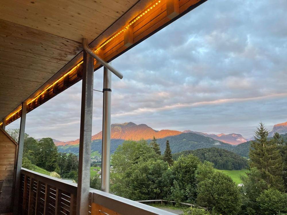 Balkon mit Holzverkleidung und stimmungsvoller Beleuchtung, bietet einen malerischen Bergblick bei Sonnenuntergang.