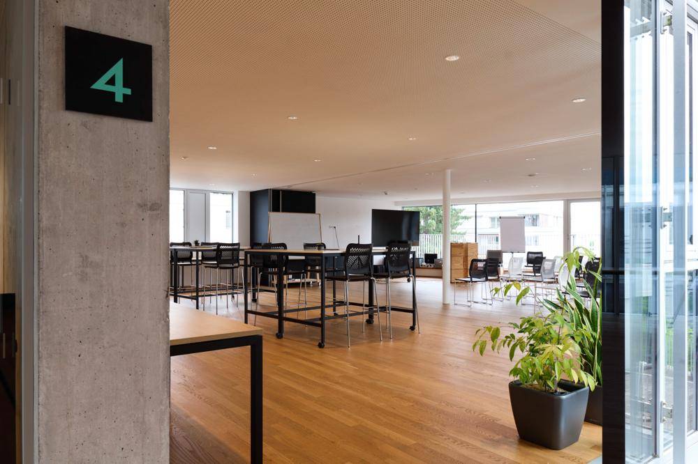 Heller, offener Bürobereich mit Holzboden, modernen Möbeln und Pflanzen als Dekoration.