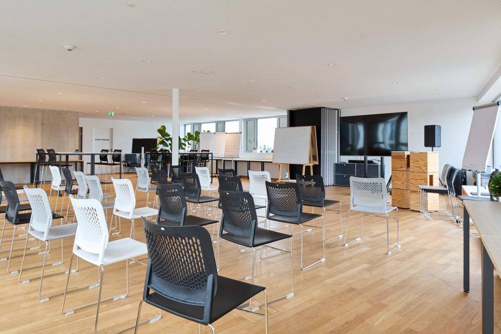 Großer Konferenzraum mit Reihenbestuhlung, einem großen Bildschirm und Whiteboards, ideal für Präsentationen und Schulungen.