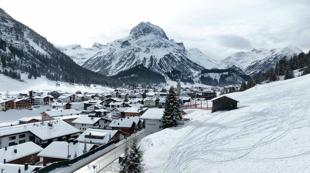 Malerisches Bergdorf in einer weiten, verschneiten Landschaft mit imposanten Gipfeln im Hintergrund, idyllisch und ruhig.